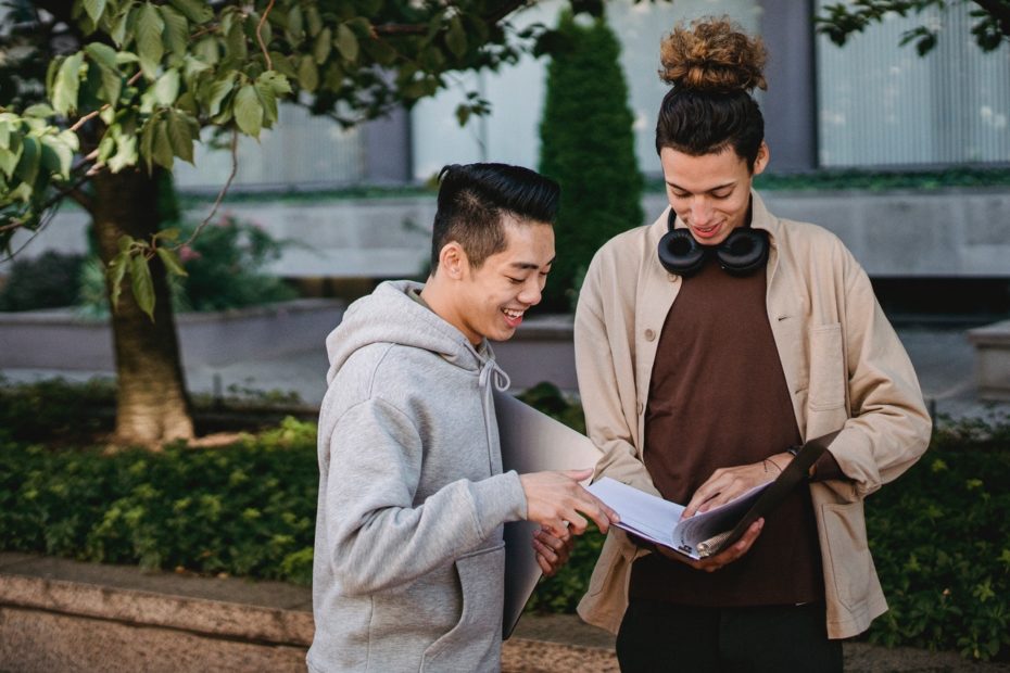 Young college students looking at notebook outside on campus.