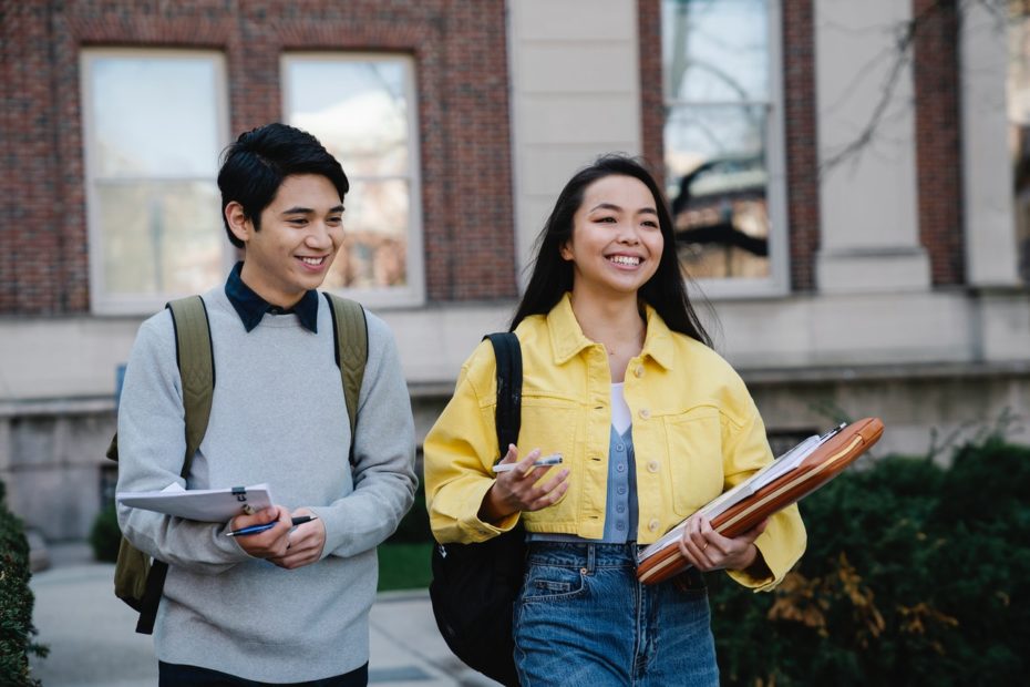 Two young college students walking to class smiling.