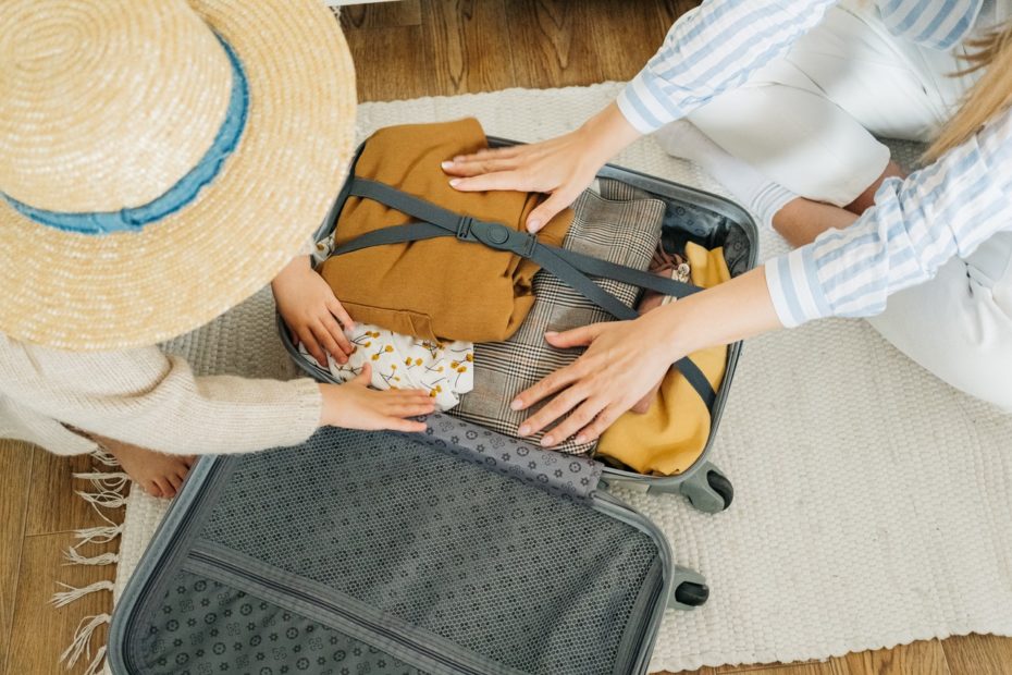 A mother and her daughter packing their suitcase before a bus trip.